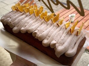 A whole chocolate orange loaf cake with chocolate frosting and decorated with slices of candied orange.